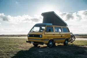 Cette image montre un camping-car attelant un panneau solaire au soleil de midi.